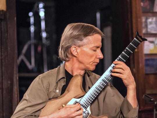 John Stowell profile shot with guitar