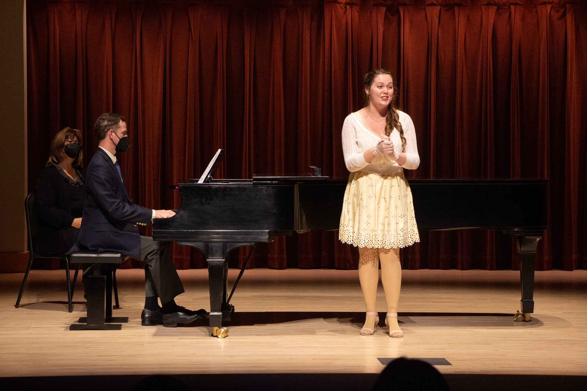 Singer in a yellow outfit on stage with a piano accompanist