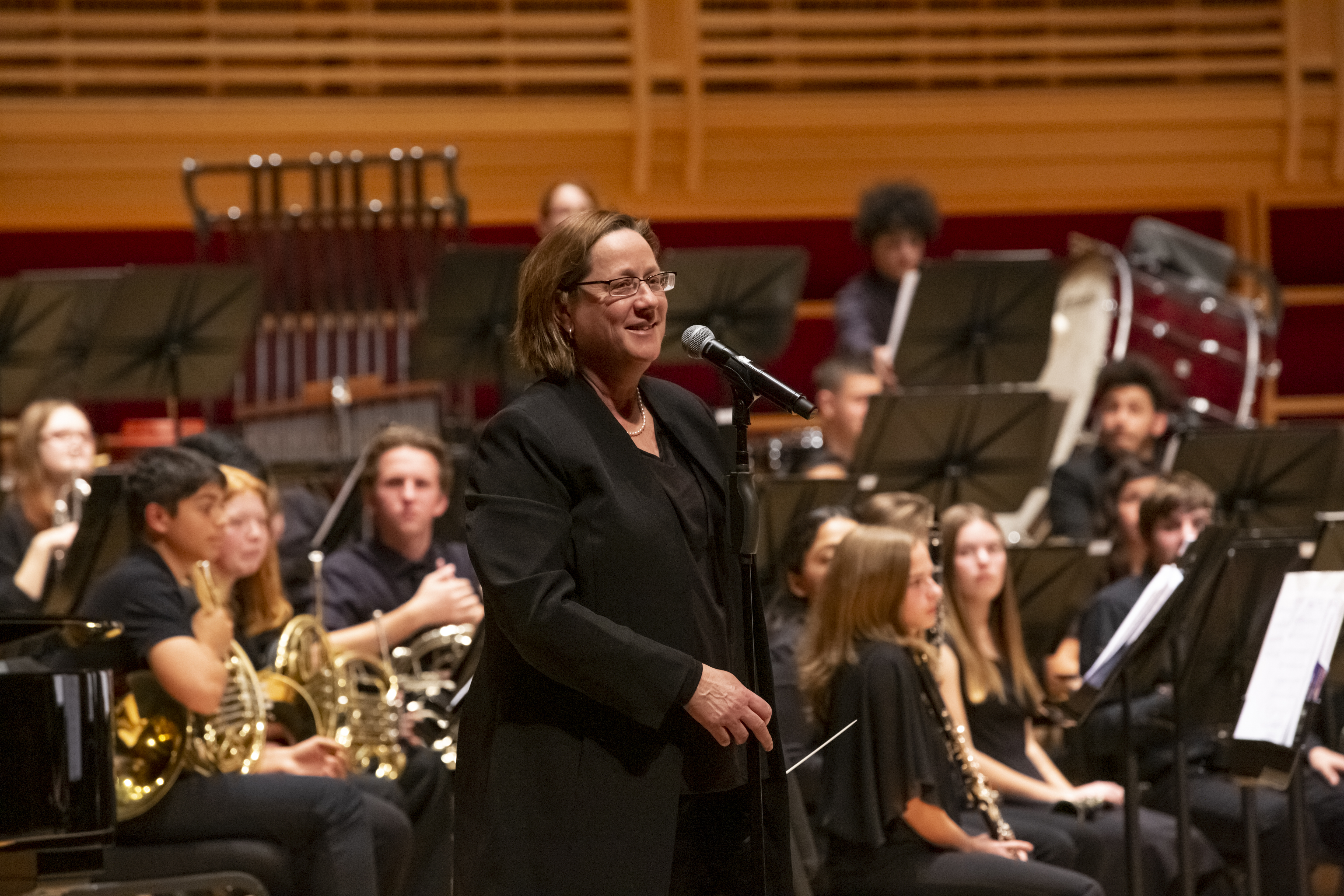 Dr. Mieder standing in front of a microphone in front of the Noma Winds band on stage