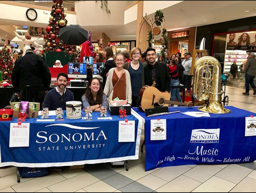 Students behind a Sonoma State table in the middle of the mall at Christmas time